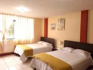 um quarto de hotel com duas camas e uma janela em Apartments & Rooms Helena em Trujillo