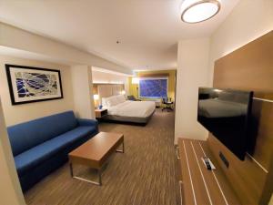 リンウッドにあるHoliday Inn Express Hotel & Suites Seattle North - Lynnwood, an IHG Hotelのソファ、ベッド、テレビが備わるホテルルームです。