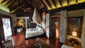 
a bedroom with a large bed and a large window at Le Domaine de L'Orangeraie Resort and Spa in La Digue
