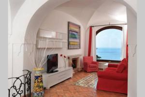 Una sala de estar con un sofá rojo y un televisor. en Villa Profumo di Mare con vista mozzafiato, en Positano