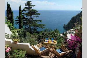 Un patio con mesa y sillas y el mar. en Villa Profumo di Mare con vista mozzafiato, en Positano