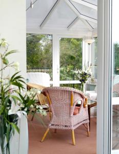 a screened porch with a wicker chair and a table at The Long Range in Budleigh Salterton