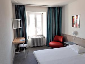une chambre d'hôtel avec un lit, une chaise et une fenêtre dans l'établissement Hôtel de France, à Sainte-Croix