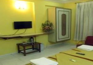 a living room with a couch and a tv on the wall at Hotel Krishna in Silvassa