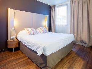 a bedroom with a large bed with white sheets and pillows at Campanile PRIME - Marseille Aubagne in Aubagne