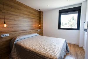 a bedroom with a bed with a wooden wall at HOTEL ALCAZAR in Mula