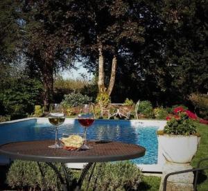 Maison des Vignes في Le Fleix: طاولة مع كأسين من النبيذ بجوار حمام السباحة