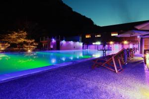 a swimming pool at night with a table and umbrellas at Amis Droles in Kawazu
