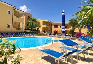 - une piscine avec des chaises longues et un parasol dans l'établissement Residence Corte Dei Venti, à Budoni
