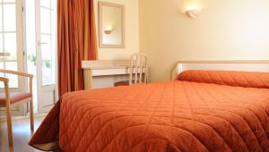 a bedroom with a bed with an orange bedspread and a desk at Relais Des Tilleuls in Hasparren