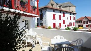 - un balcon avec des tables et des chaises blanches dans l'établissement Relais Des Tilleuls, à Hasparren