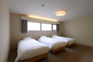 two beds in a room with a window at BEYOND HOTEL Takayama 4th in Takayama