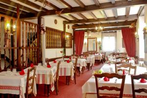 a restaurant with white tables and chairs and red curtains at Relais Des Tilleuls in Hasparren