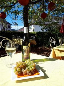 a bottle of wine and a plate of grapes on a table at Hôtel de France in Sainte-Croix