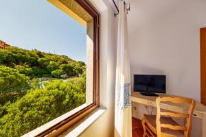 a room with a window with a desk and a television at Hotel San Trano in Luogosanto