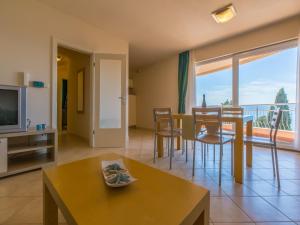 a living room with a television and a table with chairs at Apartments Villa Vanda in Selce