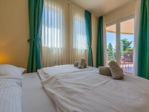 a bedroom with a large white bed with green curtains at Apartments Villa Vanda in Selce