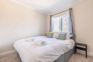 a bedroom with a large white bed with a window at Heathrow Apartment - private balcony & FREE PARKING! in Slough