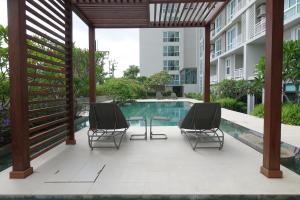a patio with two chairs and a table next to a swimming pool at The Garden 304 in Si Maha Phot