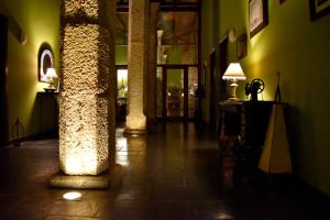 een hal met twee kolommen en een tafel met een lamp bij HOTEL RURAL A VELHA FABRICA in Valverde del Fresno