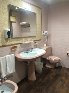 a bathroom with a sink and a toilet and a mirror at Hotel Marqués de Santillana in Torrelavega