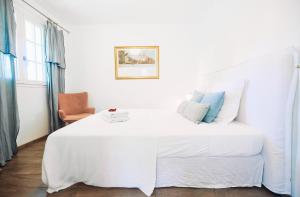 a white bedroom with a large white bed with blue pillows at Maison la pointe in Le Tampon
