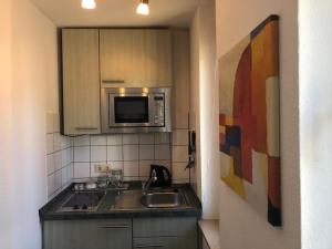eine Küche mit einer Spüle und einer Mikrowelle in der Unterkunft Apartmenthaus Somborn in Bochum
