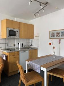 una cocina con armarios de madera y una mesa con sillas. en Apartmenthaus Somborn, en Bochum