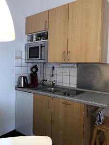 a small kitchen with a sink and a microwave at Apartmenthaus Somborn in Bochum