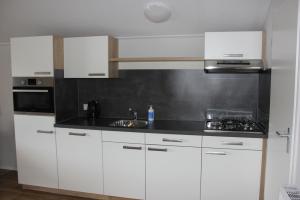 una cucina con mobili bianchi e un piano di lavoro nero di De Bijsselse Enk, Noors chalet 8 a Nunspeet Altre 5 foto