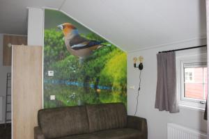 een schilderij van een vogel op een muur naast een bank bij De Bijsselse Enk, Noors chalet 9 in Nunspeet