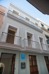 Un edificio blanco con balcones a los lados. en La Posada del Mercado, en Cádiz