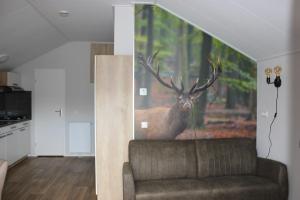 a living room with a painting of a deer on the wall at De Bijsselse Enk, Noors chalet 12 in Nunspeet