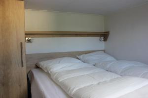 a row of white pillows lined up against a wall at De Bijsselse Enk, Noors chalet 12 in Nunspeet