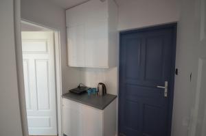 cocina con puerta azul y armario blanco en Blue Sail Sopot Apartments en Sopot