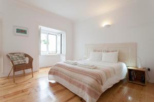 1 dormitorio blanco con 1 cama grande y 1 silla en Alfama - 28888AL, en Lisboa