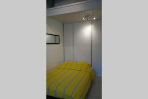 Un pequeño dormitorio con una cama amarilla en una habitación en L'Atelier à 100 m de Tarbes sud en Laloubère