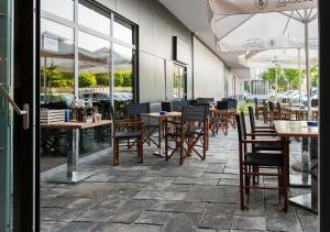 een restaurant met houten tafels, stoelen en ramen bij Urban Ring Hotel in Ljubljana