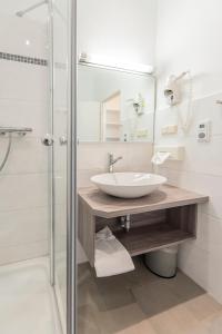 a bathroom with a sink and a shower at Hotel Aigner in Bonn