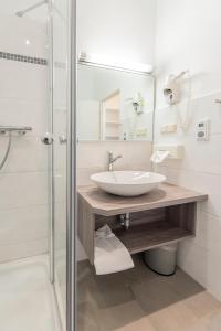 a bathroom with a sink, mirror, and bath tub at Hotel Aigner in Bonn