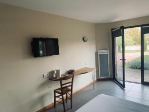 a room with a table and a television on the wall at La Grange de l’Ouche in Saint-Parize-le-Châtel