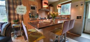 a kitchen with a counter with yellow chairs in it at Heather Cottage - Stylish 3 Bedroom Cottage, Garden, Parking, Pets Welcome in Aberdeen