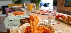 einen Tisch mit Spaghetti-Platten und Teller mit Lebensmitteln in der Unterkunft Heather Cottage Aberdeen in Aberdeen