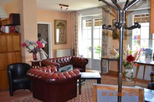 a living room with a leather couch and chairs at Hôtel Le Castel in Brissac-Quincé