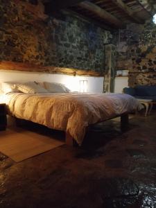 ein großes Bett in einem Zimmer mit Ziegelwand in der Unterkunft Can Masferrer in Riudarenes