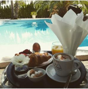 グリモーにあるMaison Prestige Saint Tropez by Roberto Geissiniのプールサイドのテーブルに朝食用の食材をトレイ
