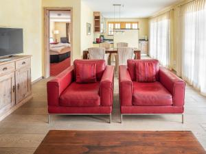 Sala de estar con 2 sillas rojas y TV en Apartment Chalet Smaragd-3 by Interhome, en Grindelwald