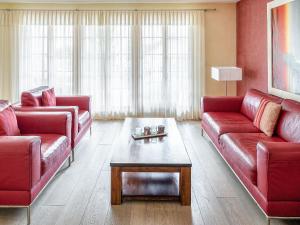 Sala de estar con 2 sofás rojos y mesa de centro en Apartment Chalet Smaragd-3 by Interhome, en Grindelwald