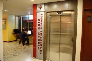 a elevator in a building with a man sitting at a desk at Hotel Elizabeth Ciudad Deportiva in Aguascalientes