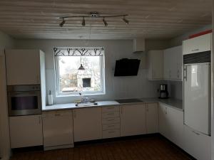VestervigにあるLogi i hus med kunst og haveの白いキャビネット、窓、シンク付きのキッチンが備わります。